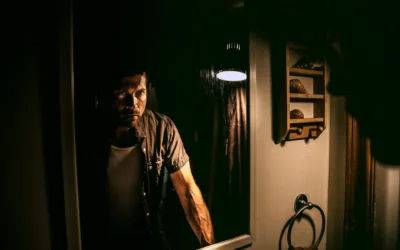 Man looking into a mirror with a serious expression, representing a concept related to schizophrenia.