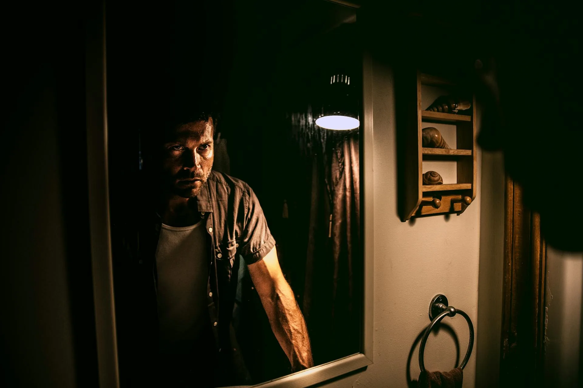 Man looking into a mirror with a serious expression, representing a concept related to schizophrenia.